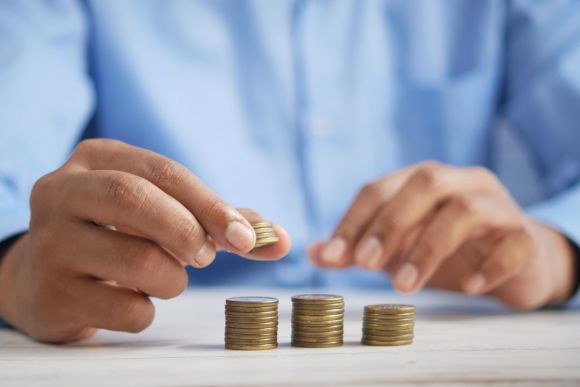 Economic - a person stacking coins on top of a table