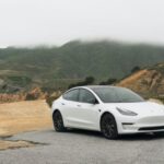 Tesla - white sedan parked beside mountain during daytime