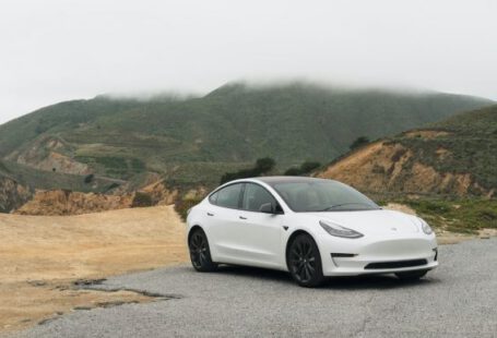 Tesla - white sedan parked beside mountain during daytime